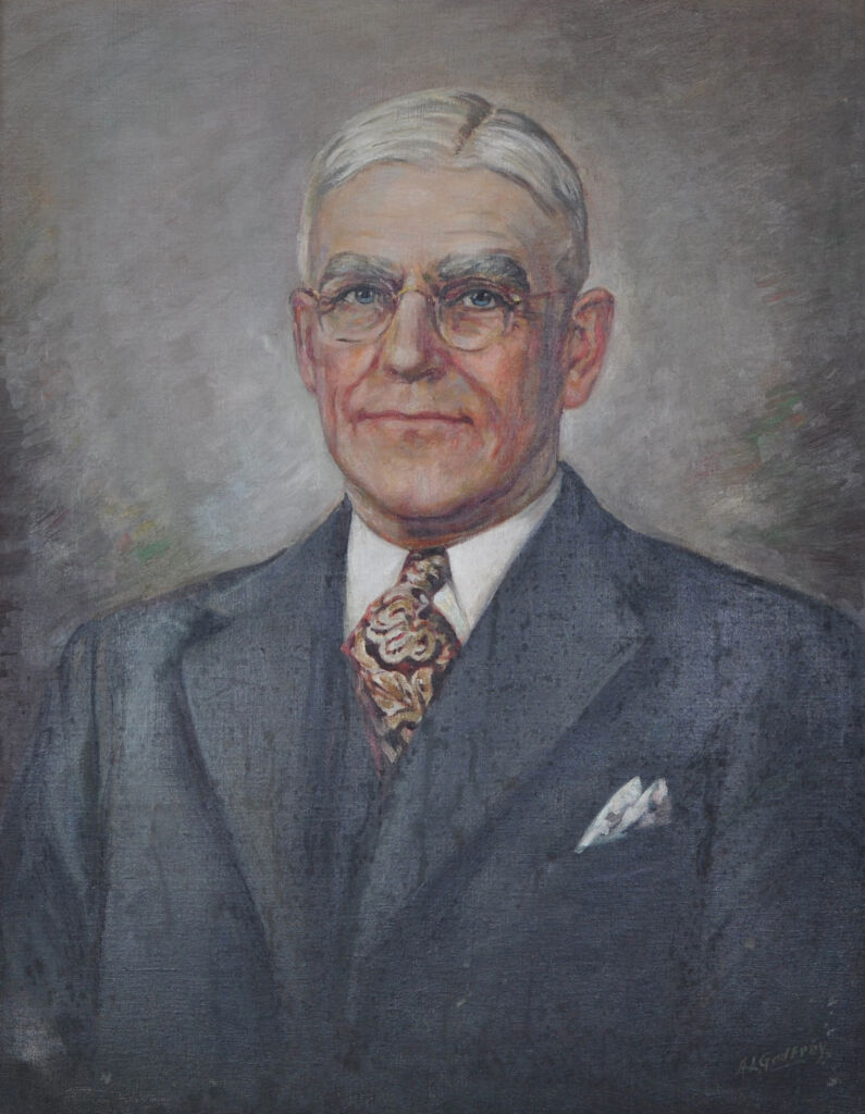 Portrait of Edward A. Mooney, a white man with gray hair, square glasses, a black suit, and paisley tie.