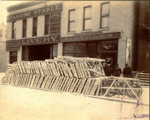 Frederick Roach Bike shop exterior and bicycles in crates. 4 people in photo.